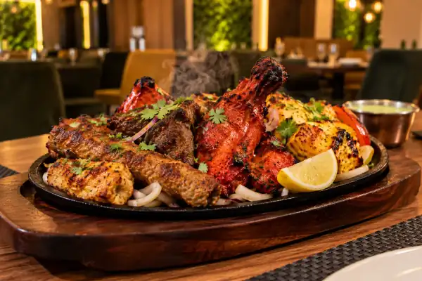 A sizzling platter of tandoori mixed grill with kebabs, chicken tikka and lemon